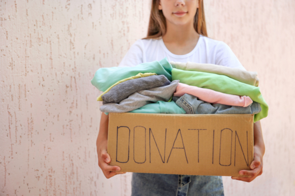 Girl holding a donation box with summer clothes